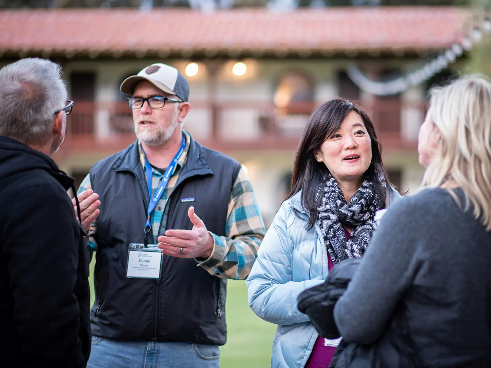 Nonprofit leaders in conversation outside at a community gathering, wearing name badges