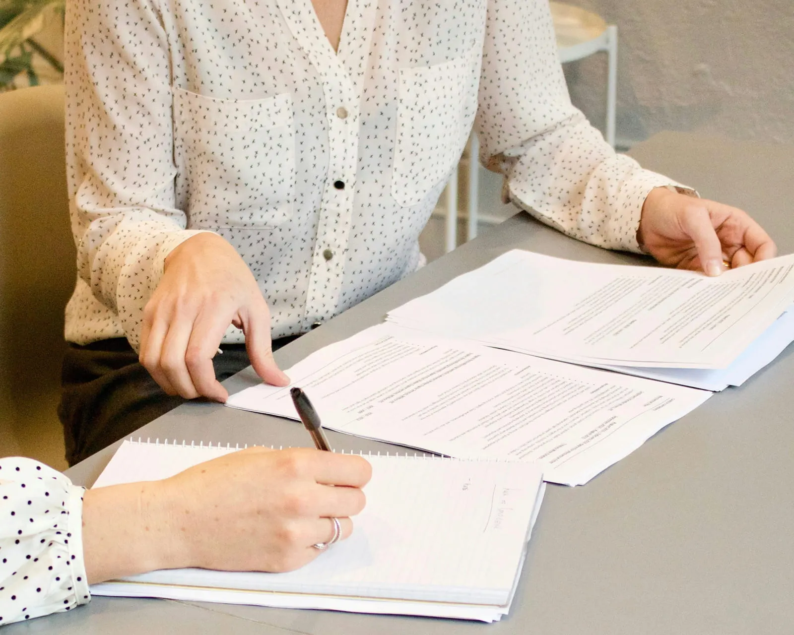 Two people reviewing printed documents at a table, one taking notes