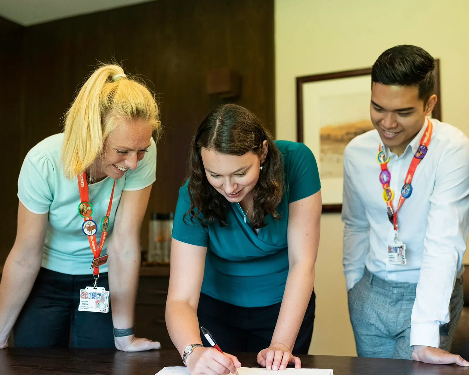 Three staff members leaning over a table, working through a document together
